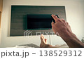 First person view of a man relaxing in hotel bed with remote control facing television. Turning on TV 138529312