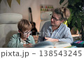 A mother tries to explain to her son how to do his homework, but, realizing that he does not understand a thing, she becomes flustered and clutches her head in her hands. They a sitting in bright room 138543245
