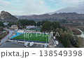 Aerial View of Scenic Football Field Surrounded by Majestic Mountains and Rolling Hills. Nature and Sports Combine in this Stunning Landscape Footage. 138549398