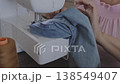 Close Up of Senior Woman Hands Sewing Denim Jeans on Machine 138549407