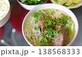 Close-up of traditional pho noodle soup eaten with chopsticks, capturing authentic Vietnamese food culture, daily life, and local dining experience in Vietnam. 138568333