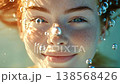 Serene portrait of a beautiful young woman with red hair and vibrant blue eyes smiling gently underwater, her face bathed in sunlight as shimmering air bubbles float around her 138568426