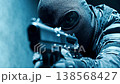 Special forces soldier in a black balaclava and goggles aiming a submachine gun down the sights. A low angle shot during a counter terrorism operation with a dramatic blue color grade 138568427