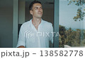 Morning lifestyle man open sliding glass door, enjoys fresh morning air, looking at green tropical backyard. Smiling man opens glass door to nature light and calm morning atmosphere starting new day. 138582778