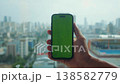Male hand holding smartphone screen green chroma key city landscape backdrop digital realm vibrant energy of urban landscape, green screen mobile phone bustling urban city chromakey. 138582779