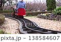 A scene of children enjoying a miniature steam locomotive ride in a park, with the locomotive starting to move. 138584607