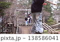 Slow-motion footage of children enjoying a Tarzan rope swing on a playground in a park, showing the start of the swing and the landing. 138586041