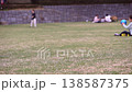 Slow-motion footage of parents and children enjoying badminton and ball games on a large grassy hill in a park. 138587375