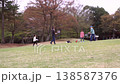 Slow-motion footage of parents and children enjoying badminton and ball games on a large grassy hill in a park. 138587376