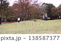 Slow-motion footage of parents and children enjoying badminton and ball games on a large grassy hill in a park. 138587377