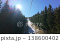 Ski Lift Pylon and Cables with Ski Slope Under Bright Blue Sky with Sun Flare 138600402