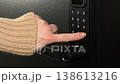 A woman opens a modern smart door lock with a digital keypad using a code. 138613216