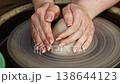 Creating pottery on the potter's wheel with hands shaping clay 138644123