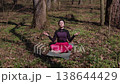 Young woman meditating in lotus position in sunny spring forest 138644429