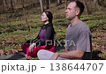 Young couple practicing yoga meditation in a sunny forest 138644707