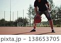 Caucasian man transfers ball from one hand to other via bounce during dribbling. Crossover with bounce of unrecognizable person on sunny day on basketball court. 138653705