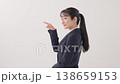 A woman in a suit making an introductory gesture. A woman in a suit making an introductory gesture. 138659153