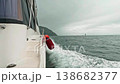 A motorboat fast sails across the sea during cloudy, choppy weather, as seen from the side. Waves splash in all directions 138682377