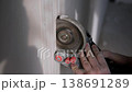 Builder forms cable grooves in plastered wall using handheld grinder during renovation works. 138691289