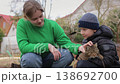Brother and sister petting a tabby cat outdoors 138692700