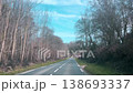Country road in France shot from car windshield, front window, dashboard view on scenic road and surrounding countryside landscape in early spring, driving ahead, trees, woods on both sides 138693337