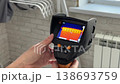 A woman checks radiators with a thermal imager. Searching for the source of heat loss. 138693759