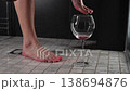 Foot fetish. A woman pours wine from a glass onto her feet in the shower. 138694876