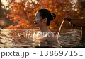 A Japanese woman warms up in an open-air bath at dusk while gazing at the autumn-colored garden 138697151