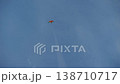 A colorful kite floats high against a bright blue sky, dancing freely in the wind. 138710717