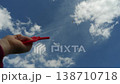 Vivid capture: the hand carefully controls the kite s string while the kite flies high overhead. 138710718