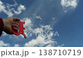 Foreground shows a hand with a kite string, as the distant kite glides against a cloudy horizon. 138710719