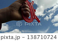 A close-up shot: a hand holds a kite s string, the kite soaring high in a clear blue sky. 138710724
