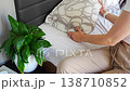 Replacing regular pillow with ergonomic orthopedic pillow on bed. Improving cervical spine support and neck alignment for better sleep, posture correction and pain relief at home. 138710852
