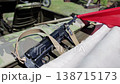 Vintage submachine gun with sling resting on camouflage pattern fabric of military vehicle, red flag partially visible in background, outdoor daytime setting, historical weapon representation 138715173