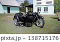 Vintage black motorcycle with sidecar parked on green grass field, background of two residential houses, one light blue with white roof, other light blue with white siding, bright sunny day 138715176