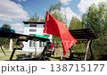 Red flag of Soviet Union with hammer and sickle emblem flying on military vehicle during daylight celebration in outdoor setting under blue sky with white clouds, historical display 138715177