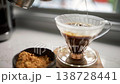Delight in the art of pour-over coffee as hot water meets ground beans. This close-up captures each moment of brewing, revealing rich colors and textures on a bright morning. 138728441
