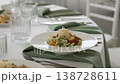 Plate with portioned salad on beautifully set table with napkins in restaurant before ceremonial reception. Food at corporate celebration in modern interior. Starter dish of Caesar salad at party. 138728611
