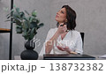 applying makeup, woman grooming, modern desk. During workday, professional woman in white clothing enhances her look with makeup brush at modern desk. 138732382