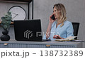 corporate woman, note taking, business communication. In modern office, businesswoman makes phone call as she types on her laptop and looks through her notes. 138732389