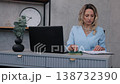 young woman, desk study, printed documents. Young woman in blue business outfit reviews and studies printed papers at her modern office desk. 138732390