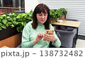 Middle-aged woman sitting in a coffee shop using her smartphone. 138732482