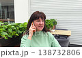 Middle-aged woman sitting in a coffee shop talking on her mobile phone 138732806