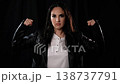Female Empowerment Concept Woman Flexing Muscles in Leather Jacket on Black Background Strength and 138737791