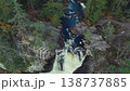 Drone footage capturing a river flowing through the forest and a waterfall cascading down a rocky cliff from directly above. 138737885