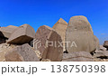 Pyramid of Khafre framed between large granite boulders with desert plateau and camels at Giza, Egypt. Unique perspective of ancient wonder under vivid blue sky. 138750398