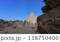 Pyramid of Khafre framed between large granite boulders with desert plateau and camels at Giza, Egypt. Unique perspective of ancient wonder under vivid blue sky. 138750400