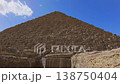 Dramatic upward view of Pyramid of Menkaure limestone blocks from base with scattered ruins at Giza, Egypt. Imposing ancient structure against blue sky. 138750404