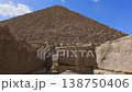Dramatic upward view of Pyramid of Menkaure limestone blocks from base with scattered ruins at Giza, Egypt. Imposing ancient structure against blue sky. 138750406