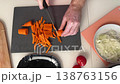 Closeup Caucasian Hands Slicing Orange Carrot On Cutting Board, Diced Red Pepper In Plate, Crisp Texture, 138763156